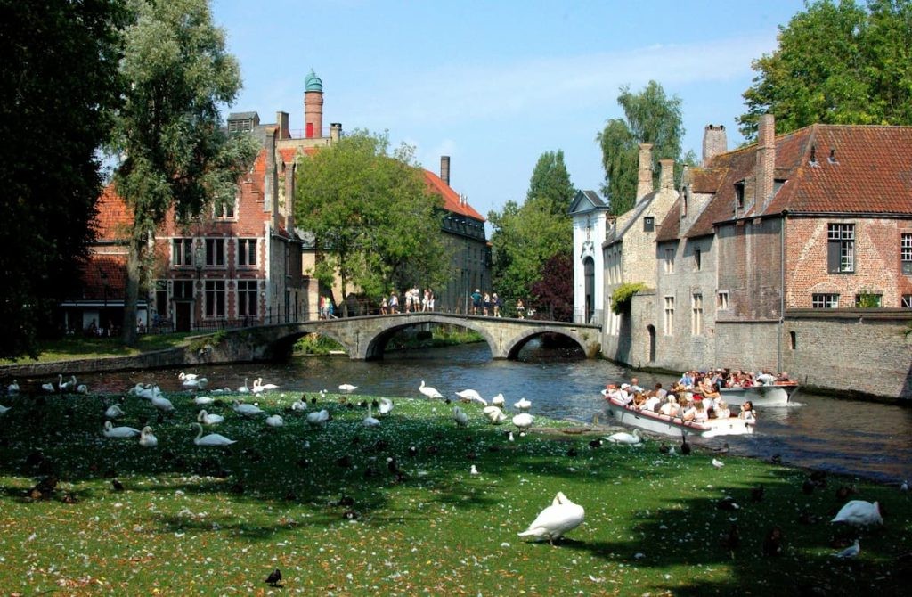 Stone bridge over a canal with swans and historic buildings in Bruges