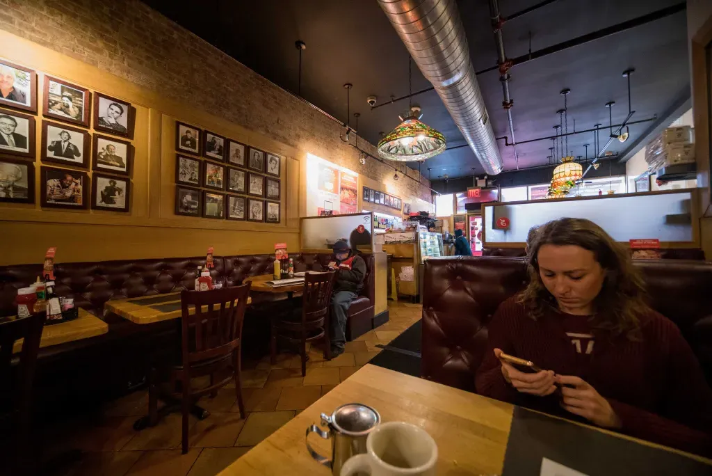 Cozy booth at Sarge’s Deli and Diner with stained-glass pendant lights and framed photos.
